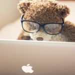 Плюшевый мишка в очках за ноутбуком