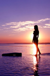 Силуэт девушки в лучах заходящего солнца над морем