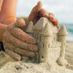 Руки закрывают маленький песочный замок