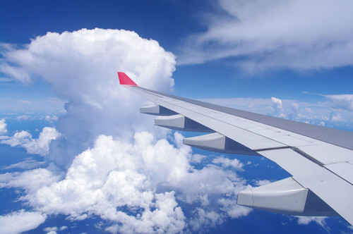 Под крылом самолета можно увидеть голубое небо и кудрявые...