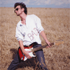 Парень в очках, играющий в поле на гитаре